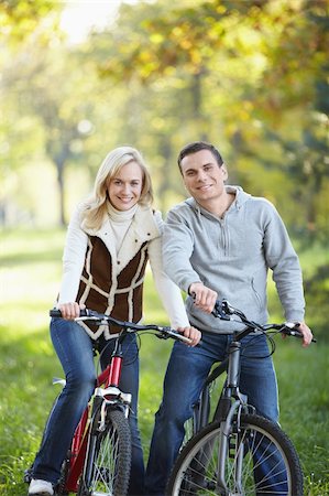 simsearch:400-04336561,k - The happy couple on bicycles in the park Fotografie stock - Microstock e Abbonamento, Codice: 400-04336544