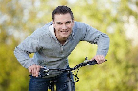 simsearch:400-04336561,k - Young attractive man riding his bicycle in the park Fotografie stock - Microstock e Abbonamento, Codice: 400-04336557