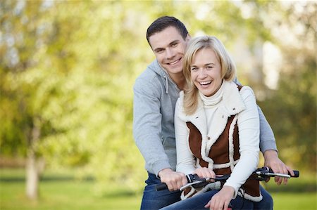 simsearch:400-04336561,k - Laughing young couple on a bike outdoors Fotografie stock - Microstock e Abbonamento, Codice: 400-04336552