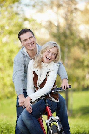 simsearch:400-04336561,k - Laughing couple on a bike in the autumn park Fotografie stock - Microstock e Abbonamento, Codice: 400-04336553