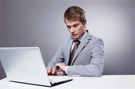 simsearch:400-04336593,k - Young businessman working with laptop on a gray background Stock Photo - Budget Royalty-Free & Subscription, Code: 400-04336568