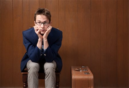 Serious Caucasian male with chin in hands and suitcase Photographie de stock - Aubaine LD & Abonnement, Code: 400-04332674