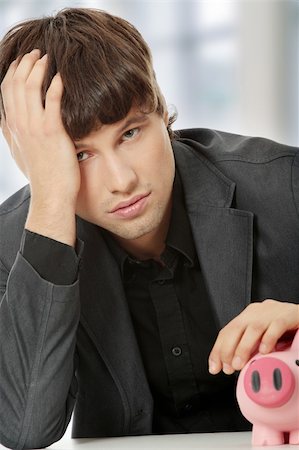 simsearch:400-04597401,k - Young depressed businessman holding piggy bank. Economy crisis concept Stock Photo - Budget Royalty-Free & Subscription, Code: 400-04333685