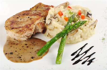 simsearch:400-04345345,k - Risotto, green asparagus and meat with gravy on a garnished white plate (Selective Focus, Focus on the head of the asparagus, part of the meat and the rice) Photographie de stock - Aubaine LD & Abonnement, Code: 400-04345349