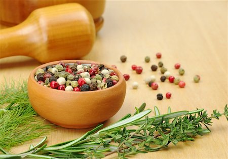 simsearch:400-04846756,k - Black, white, green and red pepper corns in a ceramic bowl with other herbs (rosemary, dill, thyme) in the foreground and a mortar and pestle in the background (Selective Focus, Focus on the front of the bowl and the pepper corns in the bowl) Stock Photo - Budget Royalty-Free & Subscription, Code: 400-04345422