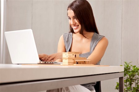 A creative professional woman working at a desk with a laptop and house model Stock Photo - Budget Royalty-Free & Subscription, Code: 400-04348402