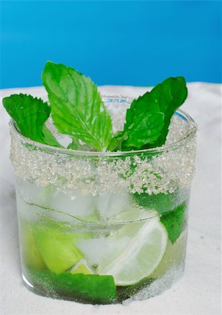 The Cocktail Mojito with Ice Cubes, Mint Leaves and Sugar Rim on Sand and with Blue Background Foto de stock - Super Valor sin royalties y Suscripción, Código: 400-04348591