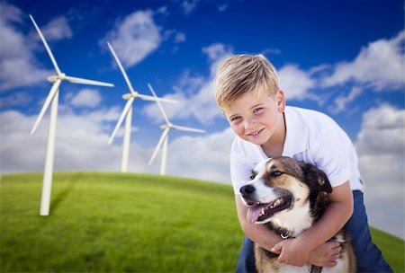 simsearch:400-07111713,k - Handsome Young Blue Eyed Boy and Dog Playing Near Wind Turbines and Grass Field. Stockbilder - Microstock & Abonnement, Bildnummer: 400-04340237