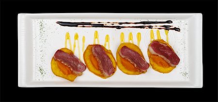 simsearch:400-05324780,k - Appetizer: Duck meat with sweet potato puree on sweet potato chip on white rectangular plate isolated on black Photographie de stock - Aubaine LD & Abonnement, Code: 400-04340487