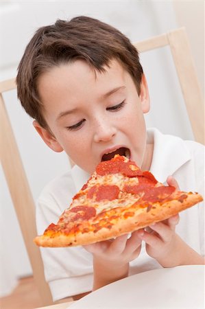 A young boy child eating a slice of pepperoni and cheese pizza Stock Photo - Budget Royalty-Free & Subscription, Code: 400-04340727