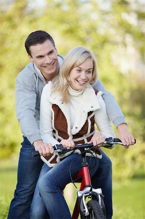 simsearch:400-04336549,k - Young couple rides a bicycle in the park Fotografie stock - Microstock e Abbonamento, Codice: 400-04340943