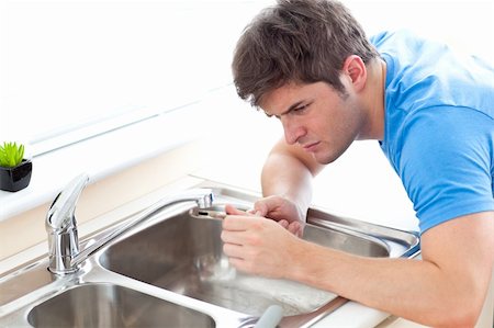 faucet repair - Concentrated man repairing his sink in the kitchen at home Photographie de stock - Aubaine LD & Abonnement, Code: 400-04341571