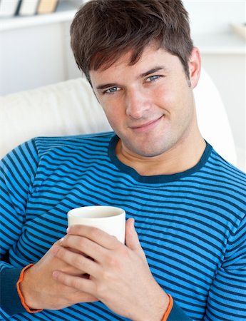 happy man resting on his couch with a cup of coffee looking at the camera Stock Photo - Budget Royalty-Free & Subscription, Code: 400-04341590