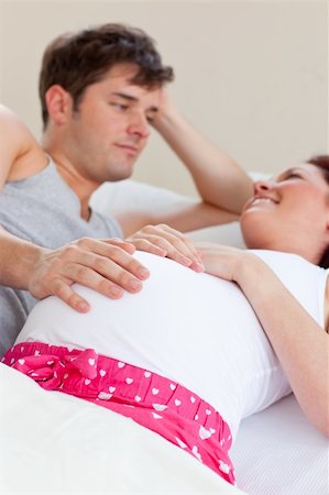 simsearch:400-07322828,k - Joyful caucasian pregnant woman lying on bed with her husband in the bedroom Fotografie stock - Microstock e Abbonamento, Codice: 400-04341678