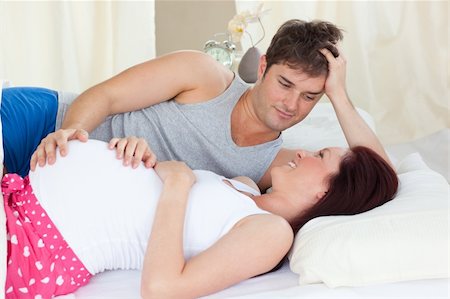 simsearch:400-07322828,k - Delighted caucasian pregnant woman lying on bed with her husband in the bedroom Fotografie stock - Microstock e Abbonamento, Codice: 400-04341694