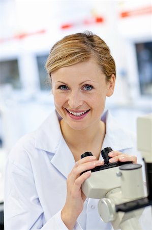 simsearch:400-05670345,k - Delighted female scientist using a microscope in her laboratory Photographie de stock - Aubaine LD & Abonnement, Code: 400-04341777