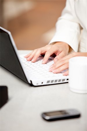 simsearch:400-04187842,k - Close-up of a busy businesswoman using her laptop with cellphone and mug on the table in her office Stock Photo - Budget Royalty-Free & Subscription, Code: 400-04341785