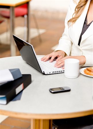 simsearch:400-04341796,k - Close-up of a busy businesswoman using her laptop with cellphone, mug and food on the table in her office Stockbilder - Microstock & Abonnement, Bildnummer: 400-04341803