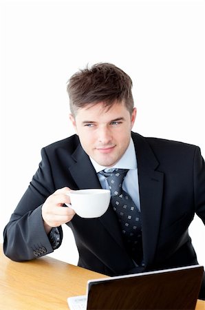 simsearch:400-05741872,k - Attractive businessman holding a cup of coffee in front of his laptop against a white background Stock Photo - Budget Royalty-Free & Subscription, Code: 400-04341836