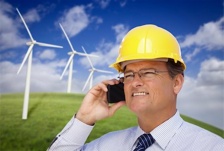 simsearch:400-04339274,k - Hard Hat Wearing Engineer on Cell Phone with Wind Turbines Behind Him. Fotografie stock - Microstock e Abbonamento, Codice: 400-04341903