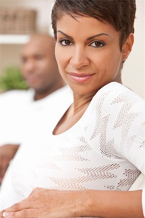 simsearch:400-04655736,k - A happy African American man and woman couple in their thirties sitting at home, the woman is in focus in the foreground the man out of focus in the background. Stockbilder - Microstock & Abonnement, Bildnummer: 400-04343276