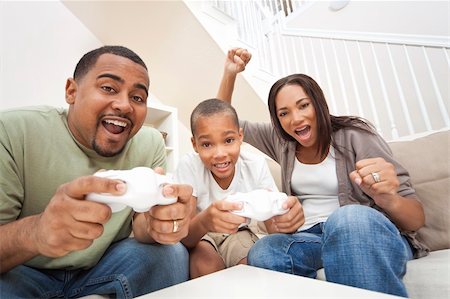 African American family, parents and son, having fun playing computer console games together, Father and son have the handset controllers and the mother is cheering the players. Stock Photo - Budget Royalty-Free & Subscription, Code: 400-04343277