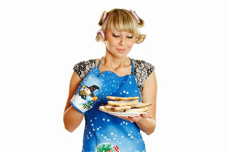 Pretty young woman in an apron and oven gloves holding a plate of gingerbread cookies. Isolated on a white background Photographie de stock - Aubaine LD & Abonnement, Code: 400-04354613