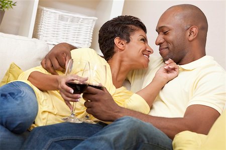 A happy African American man and woman couple in their thirties sitting at home together smiling and drinking glasses of red wine. Stock Photo - Budget Royalty-Free & Subscription, Code: 400-04356096
