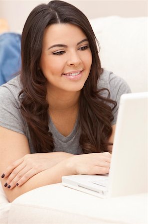 simsearch:400-04340722,k - Portrait of a beautiful young Latina Hispanic woman laying on a sofa at home relaxing and using a laptop computer Stock Photo - Budget Royalty-Free & Subscription, Code: 400-04356092