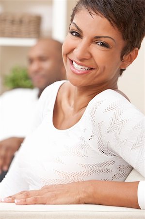 simsearch:400-04655735,k - A happy African American man and woman couple in their thirties sitting at home, the woman is in focus in the foreground the man out of focus in the background. Stockbilder - Microstock & Abonnement, Bildnummer: 400-04356622