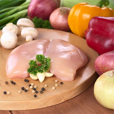 raw chicken on cutting board - Raw chicken breast with white and black pepper corns, parsley leaf and garlic surrounded by fresh vegetable (Selective Focus, Focus on the front of the meat, the garlic and the parsley) Stock Photo - Budget Royalty-Free & Subscription, Code: 400-04358368