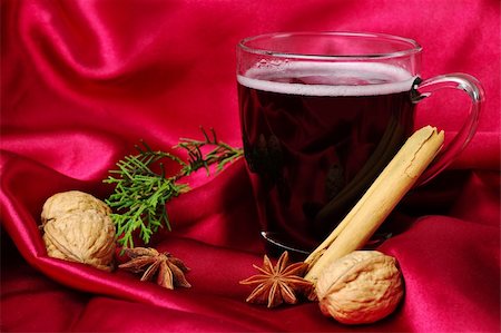 Hot spiced red wine with cinnamon, star anise, walnuts and a branch of evergreen with red background (Selective Focus) Stock Photo - Budget Royalty-Free & Subscription, Code: 400-04359323