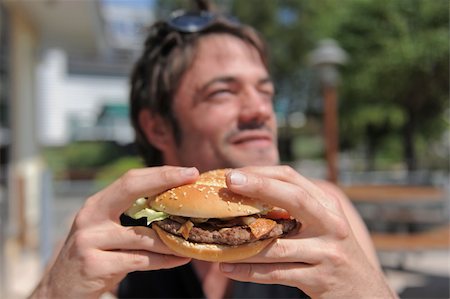 people eating in a diner - a man eating a hamburger in a fastfood, focus on the sandwitch Stock Photo - Budget Royalty-Free & Subscription, Code: 400-04359546