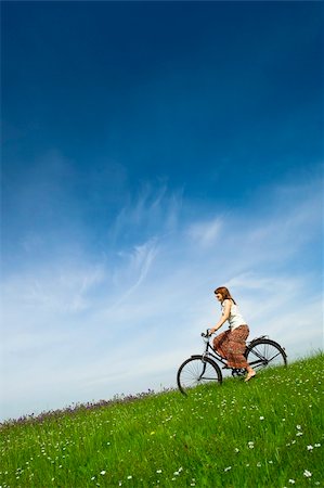 Happy young woman on a green meadow riding a bicycle Stock Photo - Budget Royalty-Free & Subscription, Code: 400-04359573