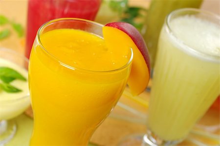 Fresh mango smoothie surrounded by watermelon, kiwi and pineapple smoothies and a cream cheese dessert on the left (Selective Focus, Focus on the front rim of the mango smoothie) Stock Photo - Budget Royalty-Free & Subscription, Code: 400-04359721