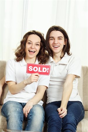 family with sold sign - Closeup of a couple sitting at home on the couch laughing, hugging and holding a plate sold Photographie de stock - Aubaine LD & Abonnement, Code: 400-04350672