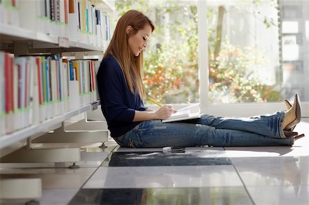 female college student sitting on floor in library, reading book and taking notes. Horizontal shape, side view, full length, copy space Stock Photo - Budget Royalty-Free & Subscription, Code: 400-04352156