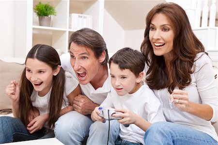 Happy family, parents, son and daughter, having fun playing video console games together, the young boy has the handset controller everyone else is cheering. Stock Photo - Budget Royalty-Free & Subscription, Code: 400-04353335