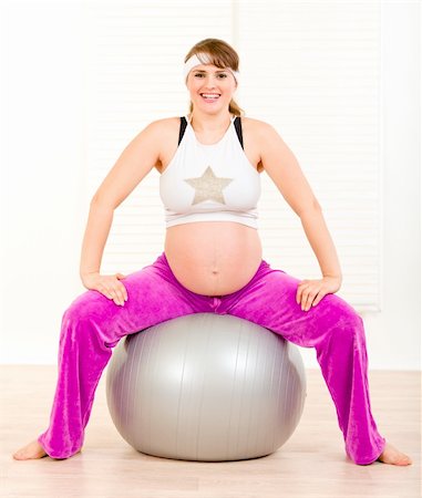Smiling beautiful pregnant female doing pilates exercises on gray ball Stock Photo - Budget Royalty-Free & Subscription, Code: 400-04353973