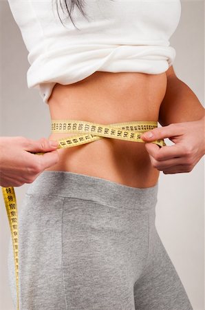 simsearch:400-04361224,k - sporty woman is measuring her waist on grey background Stock Photo - Budget Royalty-Free & Subscription, Code: 400-04361216