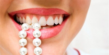 a woman smiles showing white teeth, holding a pearly necklace in to the mouth Stockbilder - Microstock & Abonnement, Bildnummer: 400-04363098