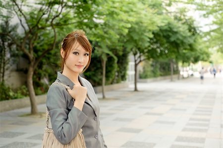 elwynn (artist) - Young business woman walking on city street with green trees and looking at you, half length closeup portrait outside of modern buildings. Foto de stock - Royalty-Free Super Valor e Assinatura, Número: 400-04363198