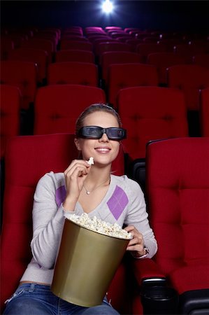 Attractive young girl with popcorn watching a movie at the cinema Stock Photo - Budget Royalty-Free & Subscription, Code: 400-04375723