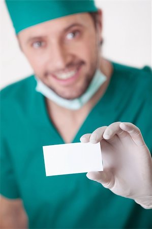 simsearch:400-04375768,k - A young surgeon holding a blank business card is isolated Foto de stock - Royalty-Free Super Valor e Assinatura, Número: 400-04375777