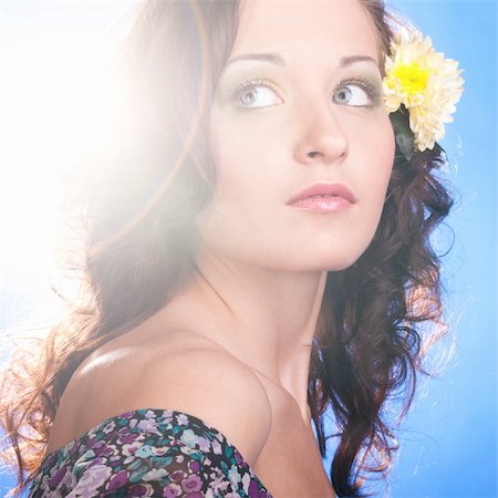 face, lens flare - beautiful smiling woman with flower is looking sideways on blue background Stock Photo - Budget Royalty-Free & Subscription, Code: 400-04376688