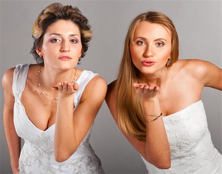 elegant bride hairstyle - two beautiful brides is standing in wedding dress on grey background and blowing a kisses Stock Photo - Budget Royalty-Free & Subscription, Code: 400-04378898