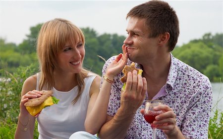 Young happy couple eating together outdoors.Young loving couple having a picnic outdoors Foto de stock - Super Valor sin royalties y Suscripción, Código: 400-04379875