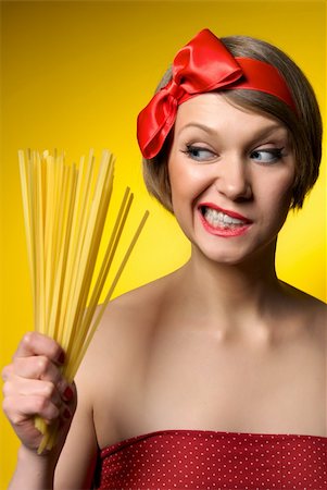 retro wife cooking - Portrait of young housewife holding pasta in her hand. Retro styled. Isolated on yellow background Stock Photo - Budget Royalty-Free & Subscription, Code: 400-04370588