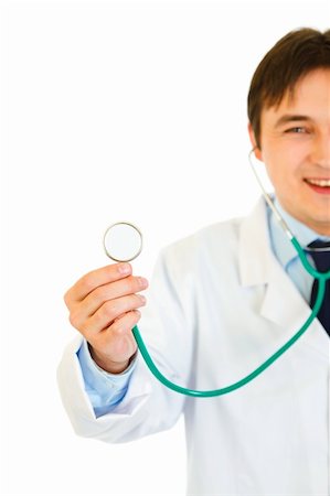 simsearch:400-04351236,k - Smiling young medical doctor  holding up stethoscope isolated on white. Close-up. Photographie de stock - Aubaine LD & Abonnement, Code: 400-04371558