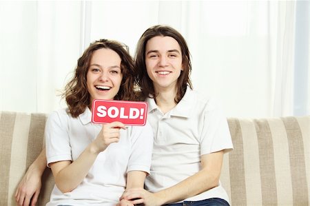 family with sold sign - Closeup of a couple sitting at home on the couch laughing, hugging and holding a plate sold Stock Photo - Budget Royalty-Free & Subscription, Code: 400-04373824